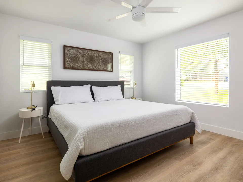 Bedroom with a grey upholstered bed below a carved wood panel
