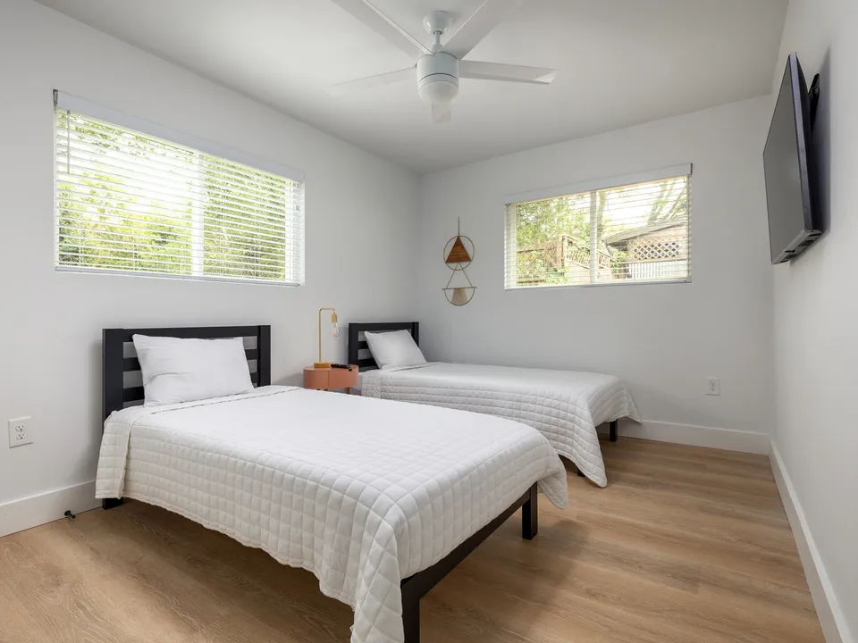 Bedroom with two beds, a ceiling fan and a wall-mounted TV