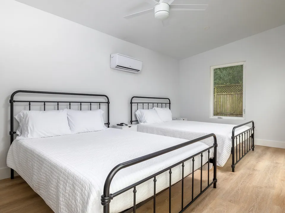 Bedroom with two black iron beds and a mini split