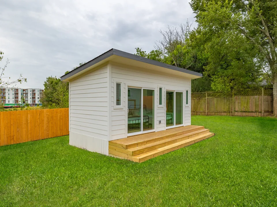 Detached studio with glass sliding doors and wood steps in the backyard