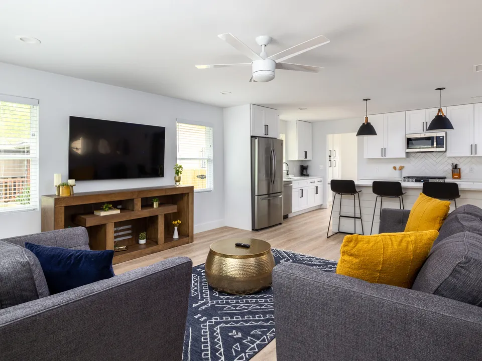 Living room with grey sofas, a TV console and the kitchen beyond