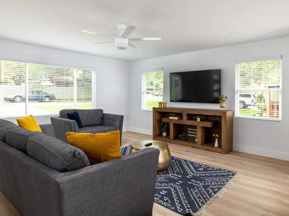 Living room with grey sofas, yellow pillows and a blue patterned rug