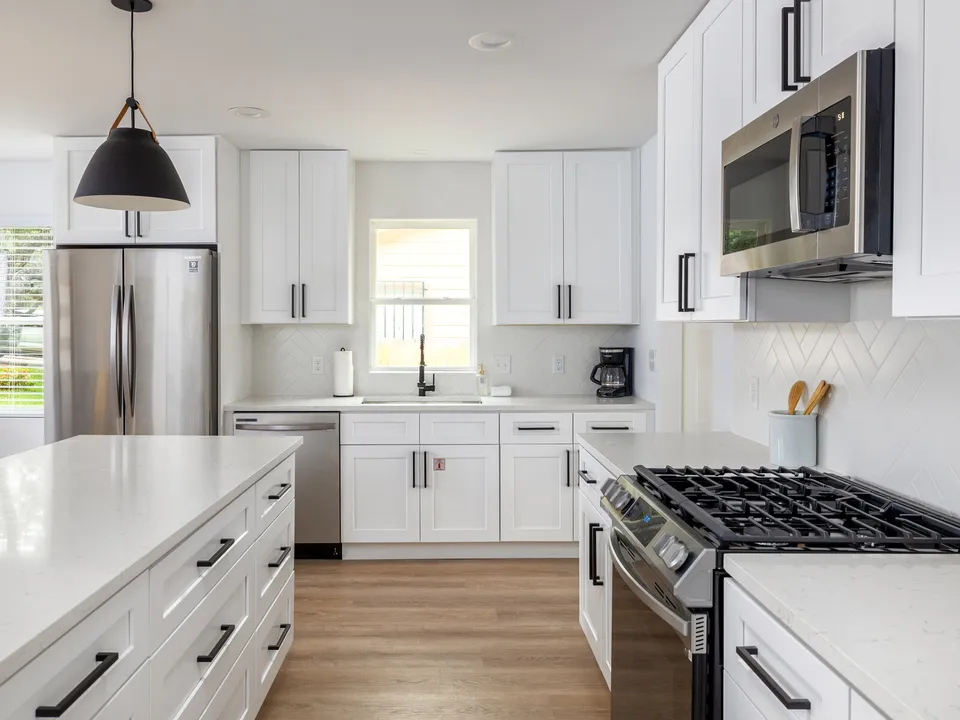 White shaker kitchen with a large island, black pendants and a gas range