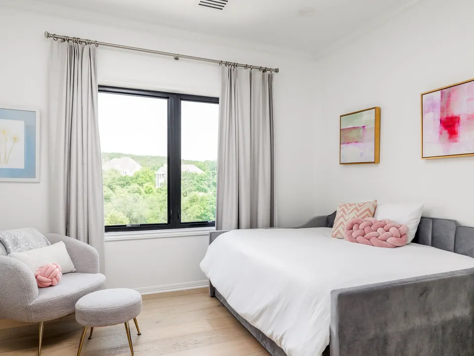 Bedroom with a grey upholstered bed, an accent chair and a window