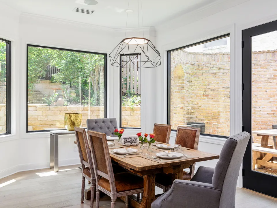 Breakfast nook with a farmhouse table in a bay of black-framed windows