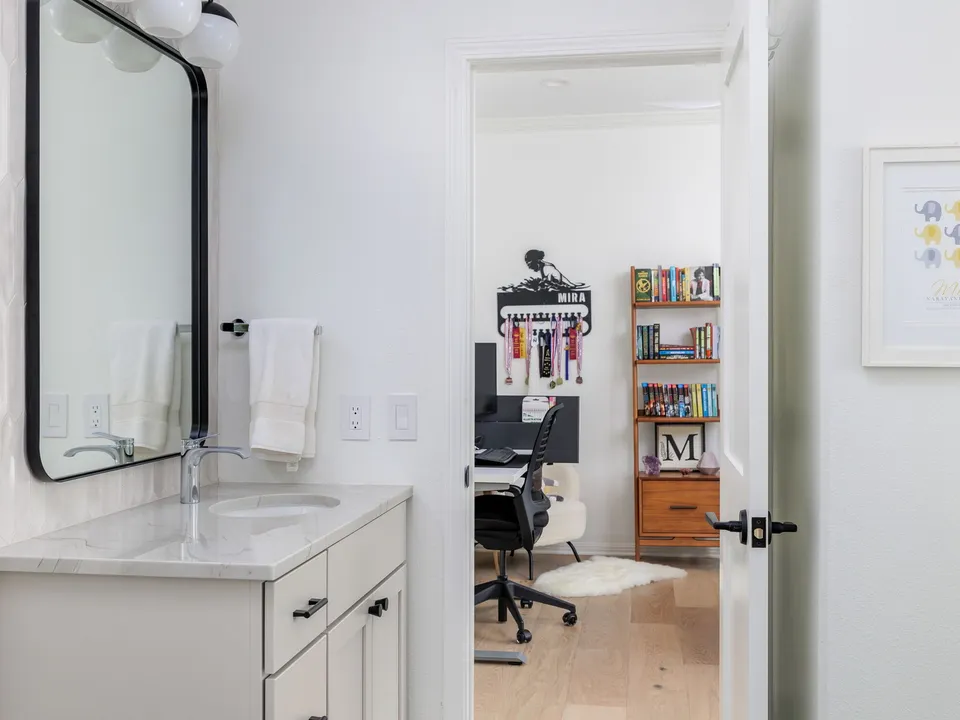 Jack and Jill bath vanity with a black mirror, open to a kids' room