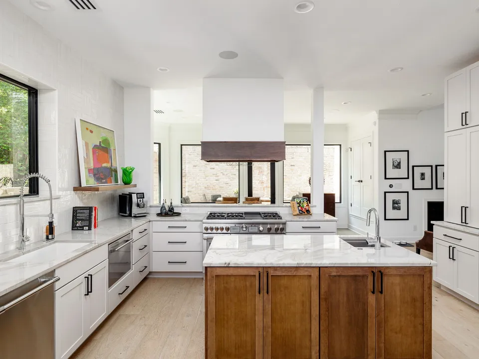Kitchen with a stained wood island and marble counters in front of white cabinets