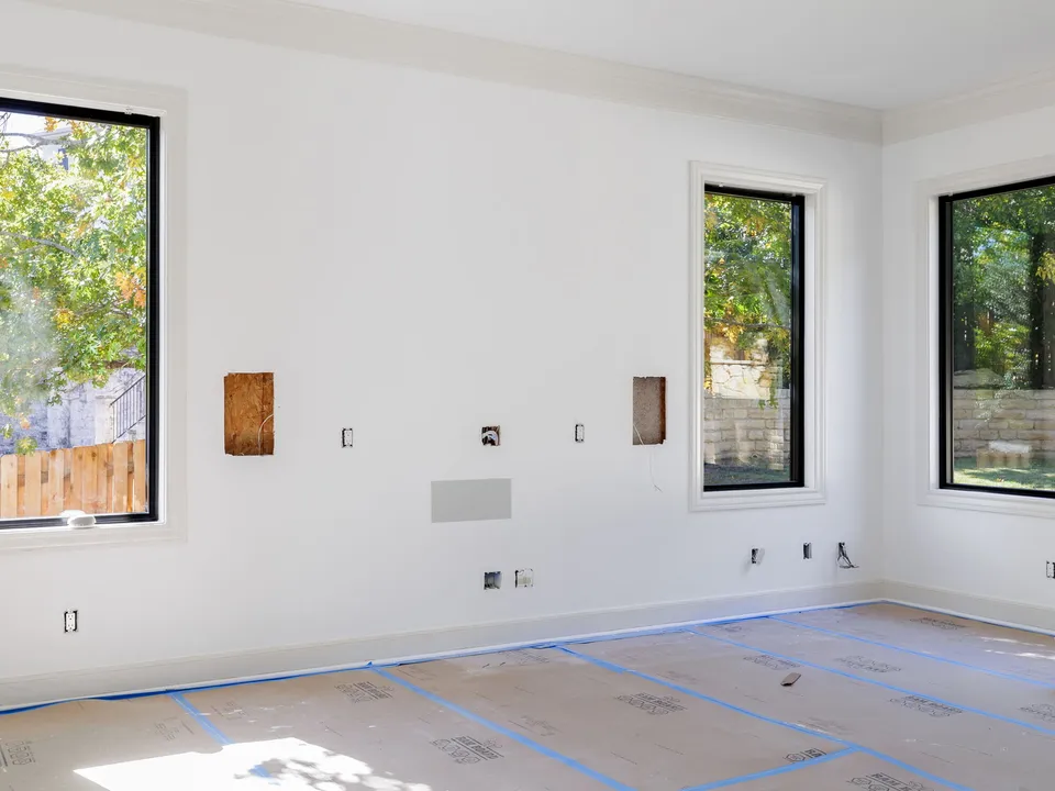 Living room before the remodel, stripped to bare walls with the floor covered