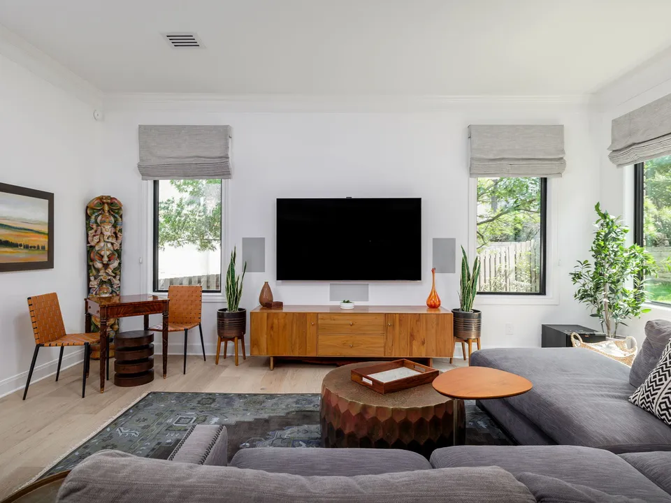 Living room with a grey sectional, a round wood coffee table and a walnut media console