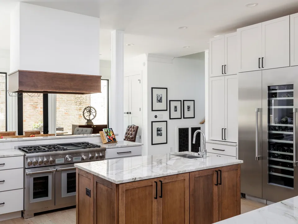 Range wall with a white and wood hood, a stainless range and a built-in refrigerator
