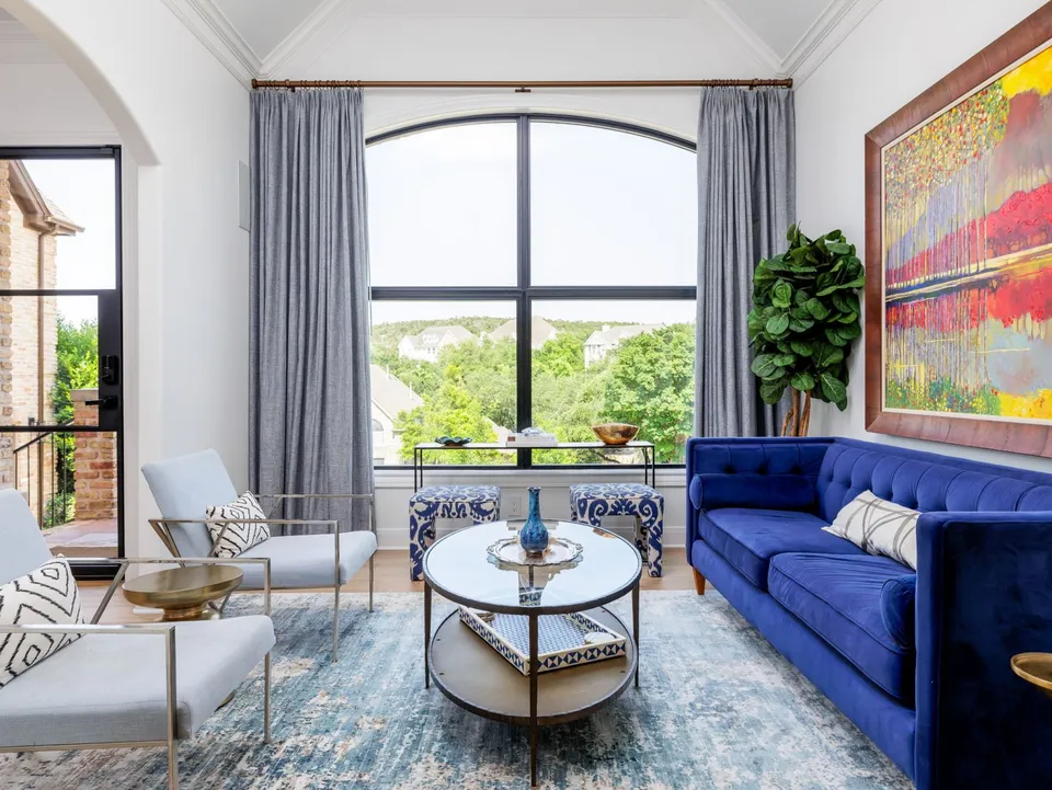Sitting room with a blue velvet sofa and a large arched window