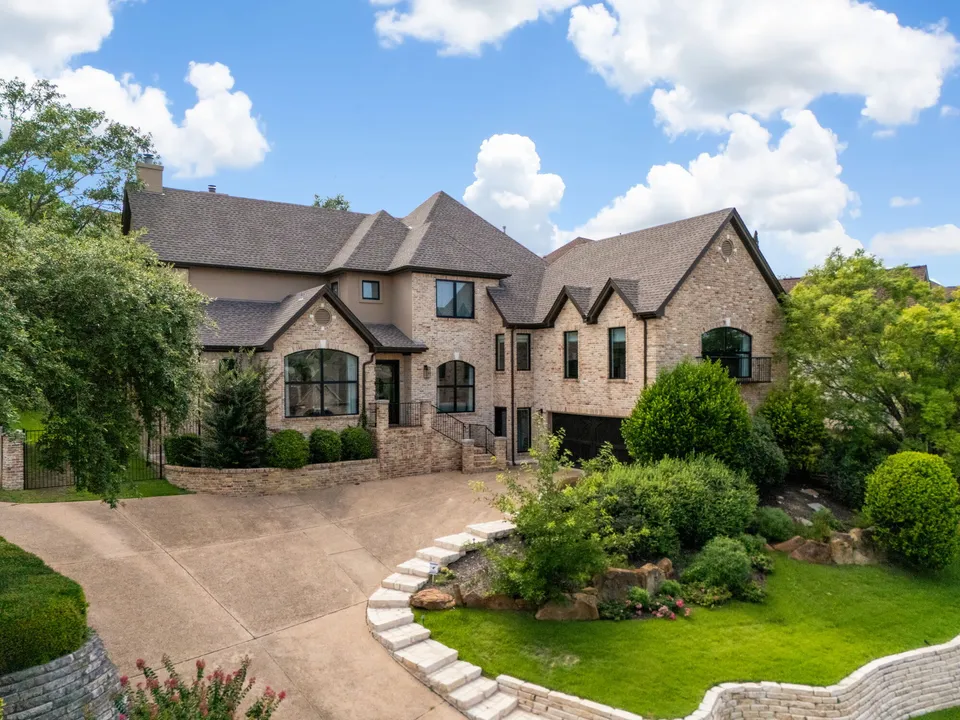 Two-story stone house with a curved driveway and a landscaped front yard