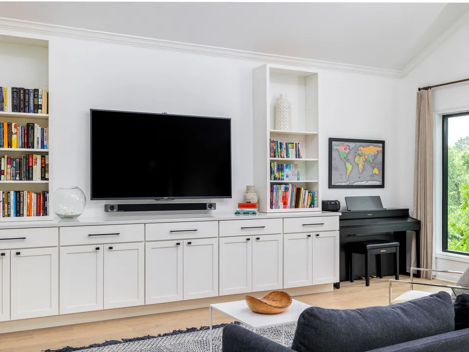 White built-in media wall with bookshelves and a piano