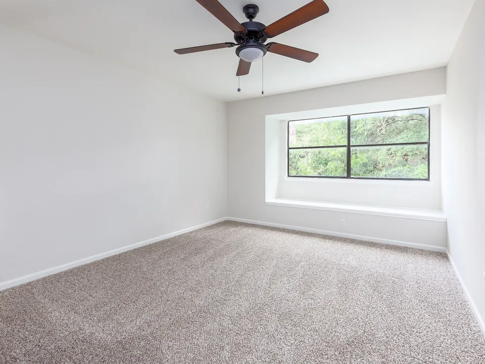 Carpeted bedroom with a bay window and a ceiling fan