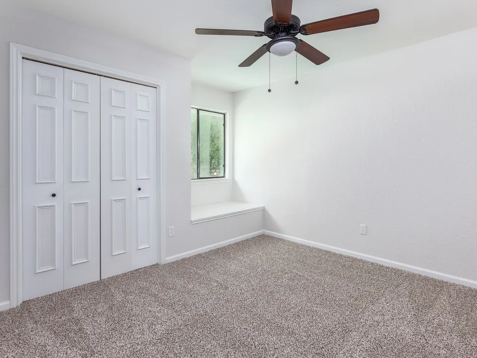 Carpeted bedroom with a double closet and a window seat