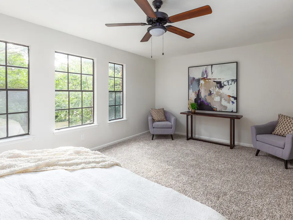 Carpeted primary bedroom with three windows and a sitting area