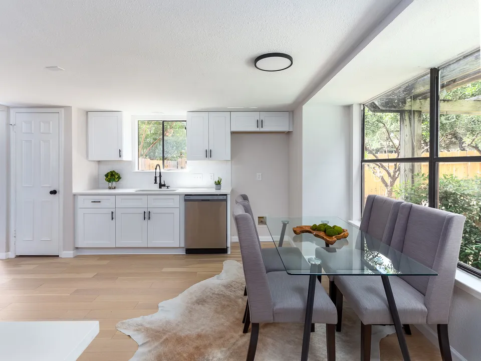 Dining area with a glass table and grey chairs beside the kitchen
