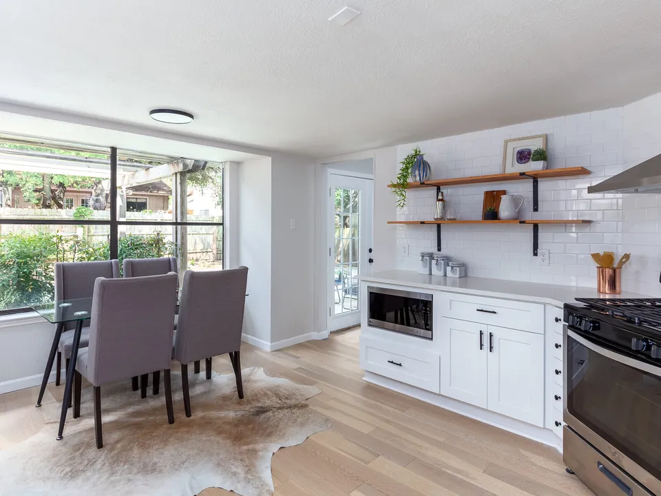 Dining area with a glass table in a window bay beside the kitchen