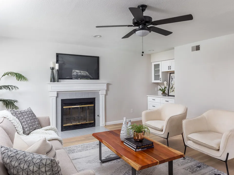 Living room with a painted fireplace, a TV and cream armchairs