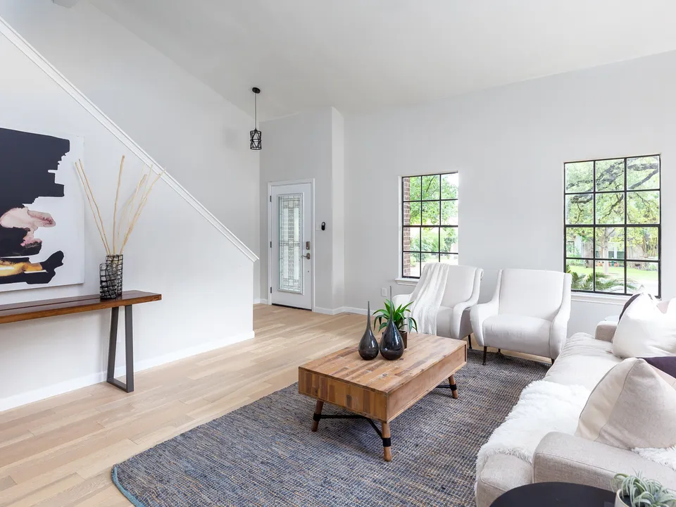 Living room with white sofas and a wood coffee table below the stairs