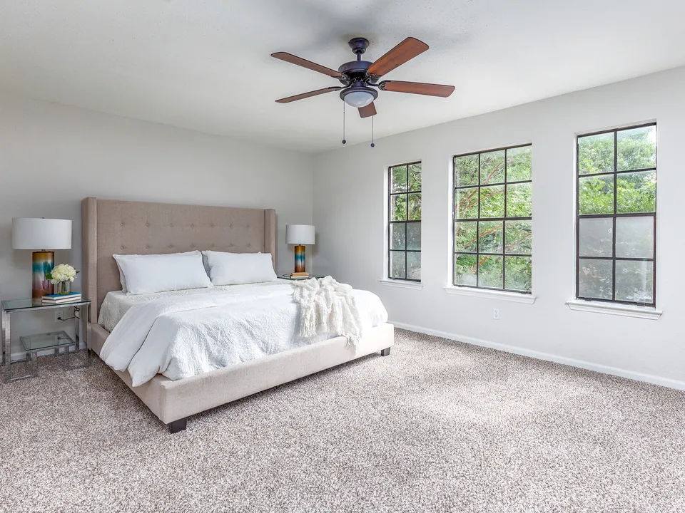 Primary bedroom with an upholstered bed and black-framed windows