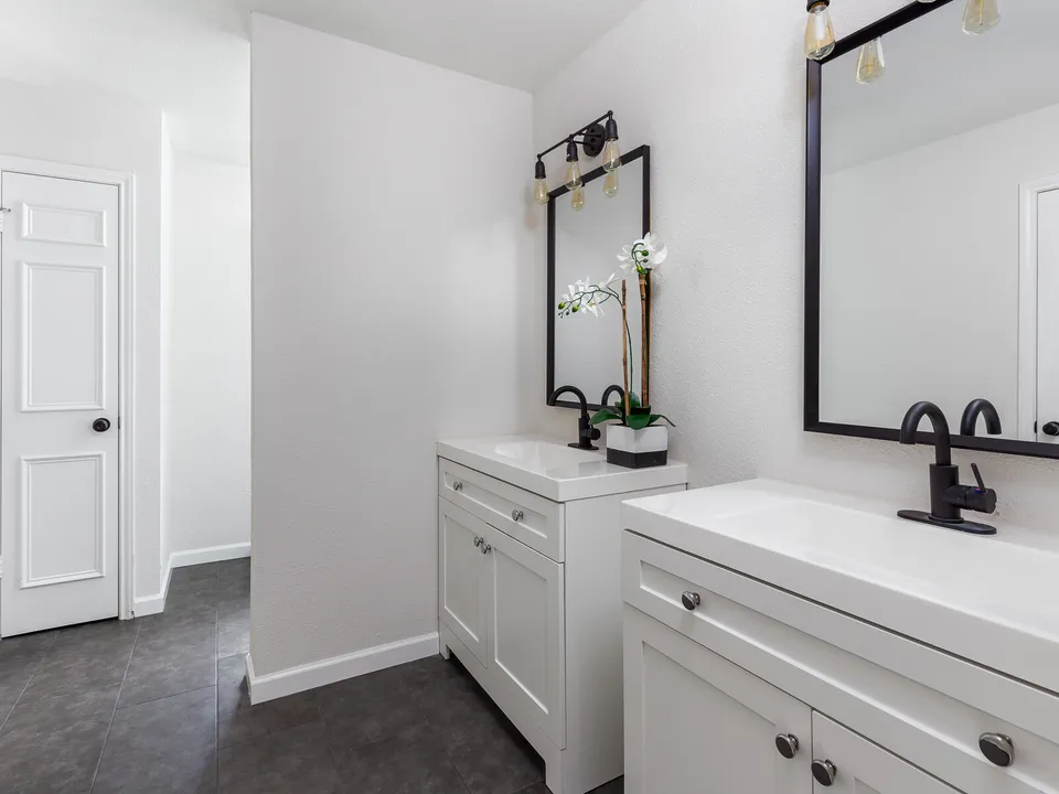 Two white vanities with black mirrors and fixtures