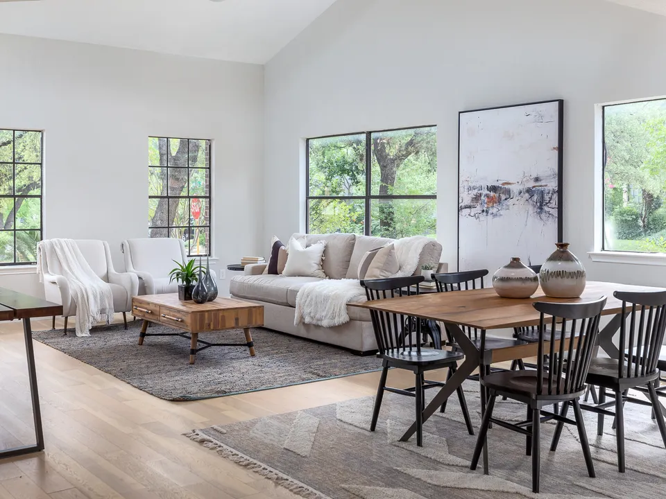 Vaulted living room with tall windows and a wood dining table