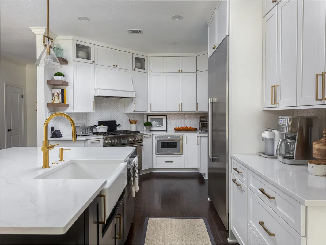 White kitchen remodel with a farmhouse sink and brass faucet