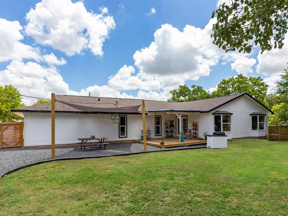 Back of the house with a covered patio, a gravel path and a new fence