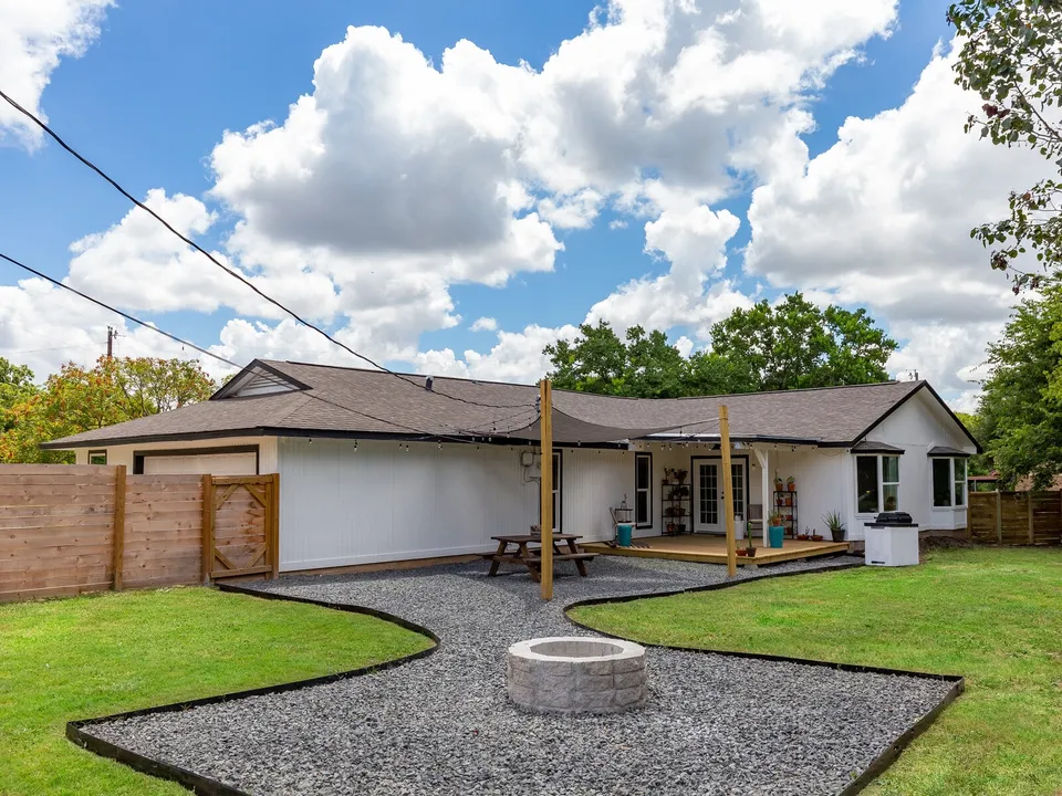Backyard with a gravel path to a stone fire pit and a cedar fence