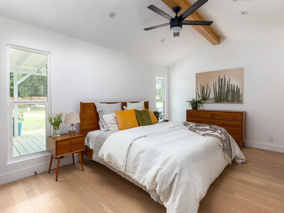 Bedroom with a beam ceiling, a wood bed and a cactus painting