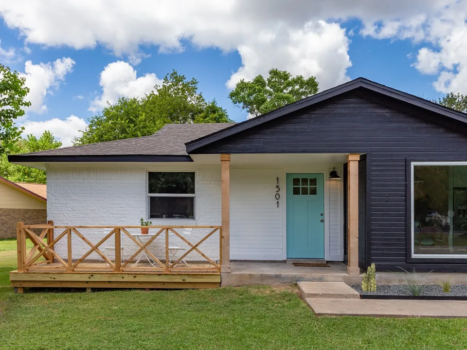 Covered front porch with a cedar railing and an aqua door on the navy and white house