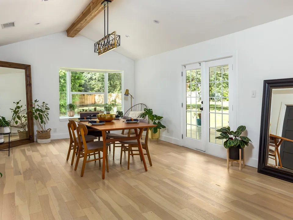 Dining area after the remodel, with a beam ceiling, French doors and light oak floors