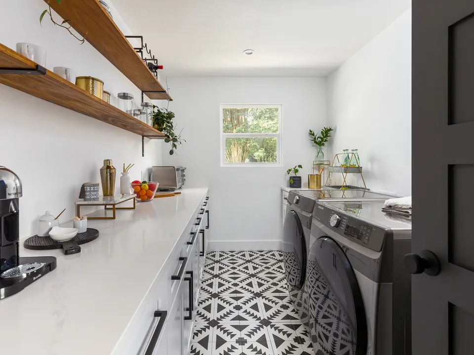 Laundry room with walnut shelves, a white counter and black and white patterned tile