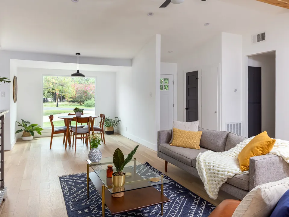 Living room with a glass coffee table and a dining area in front of a big window