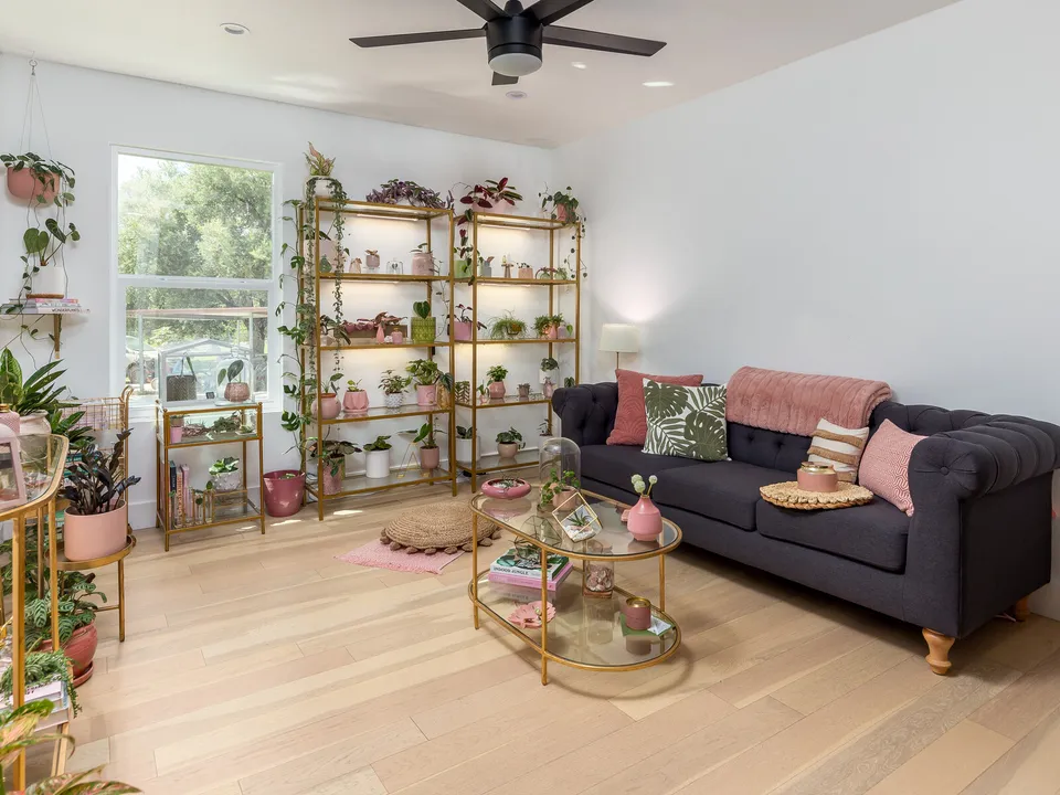 Sitting room with a navy tufted sofa and brass plant shelves by a window