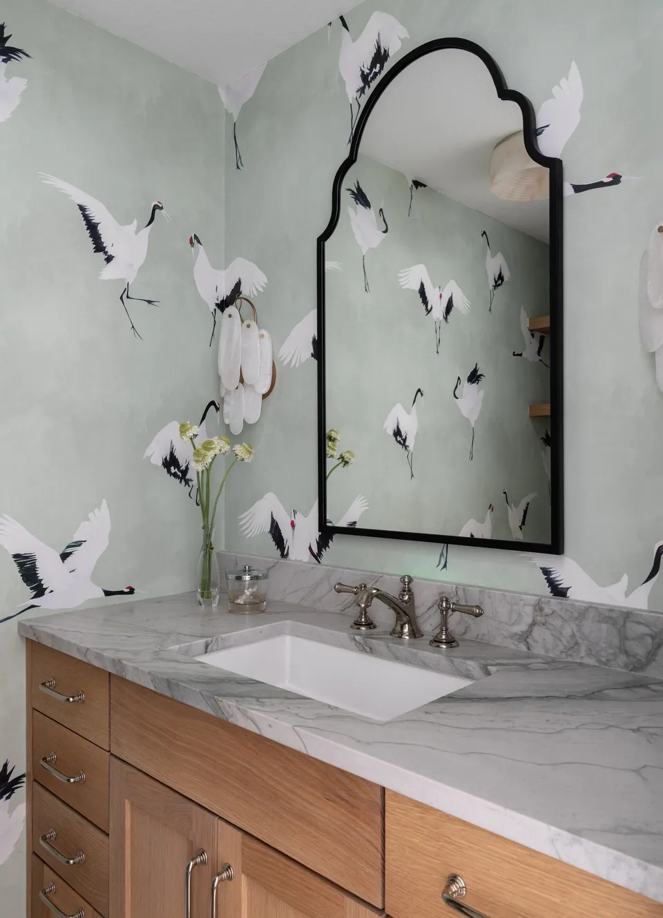 Bathroom with crane wallpaper, an arched black mirror and a marble-topped oak vanity