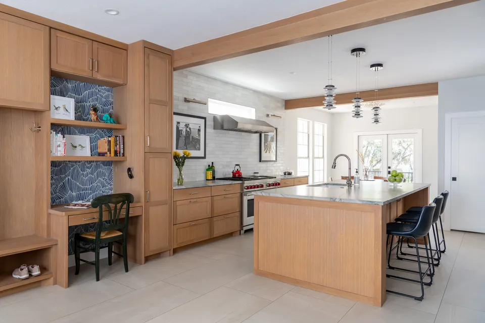 Kitchen after the renovation, with white oak cabinets, a desk nook and a marble island