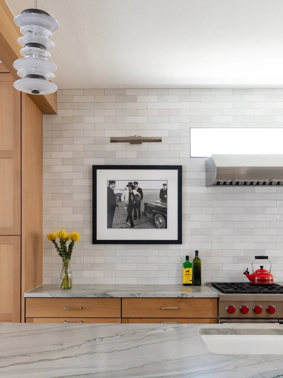 Range wall with white tile, a stainless hood and a framed black and white photo