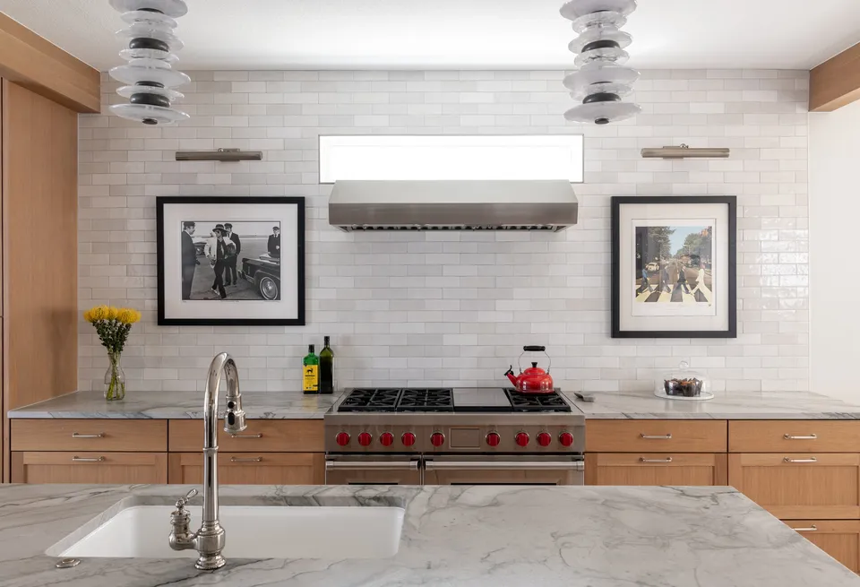 Undermount sink in the marble island facing the range wall and glass pendants