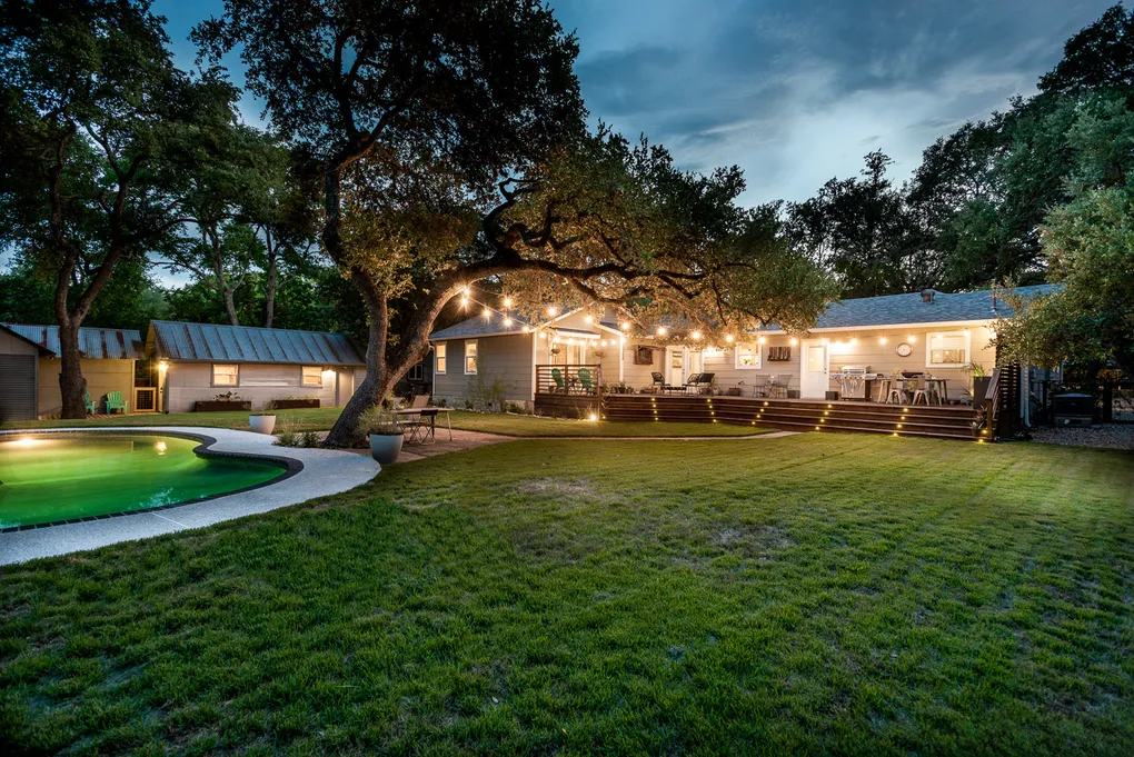 Backyard patio and lawn lit at dusk