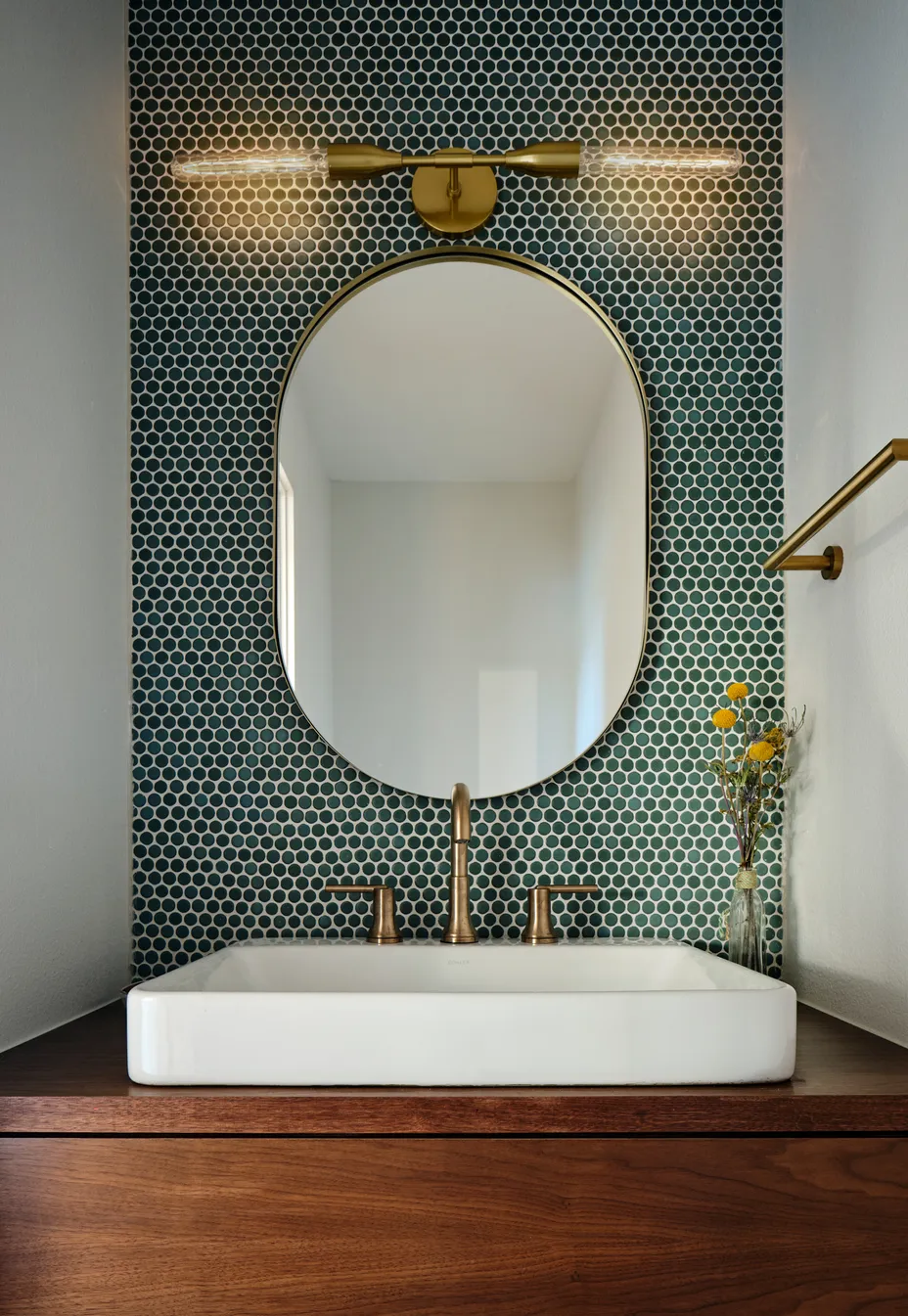 Powder bath with green hexagon tile and an oval brass mirror