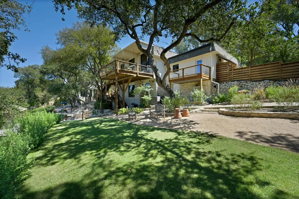 Back of the house with decks above a sloping lawn