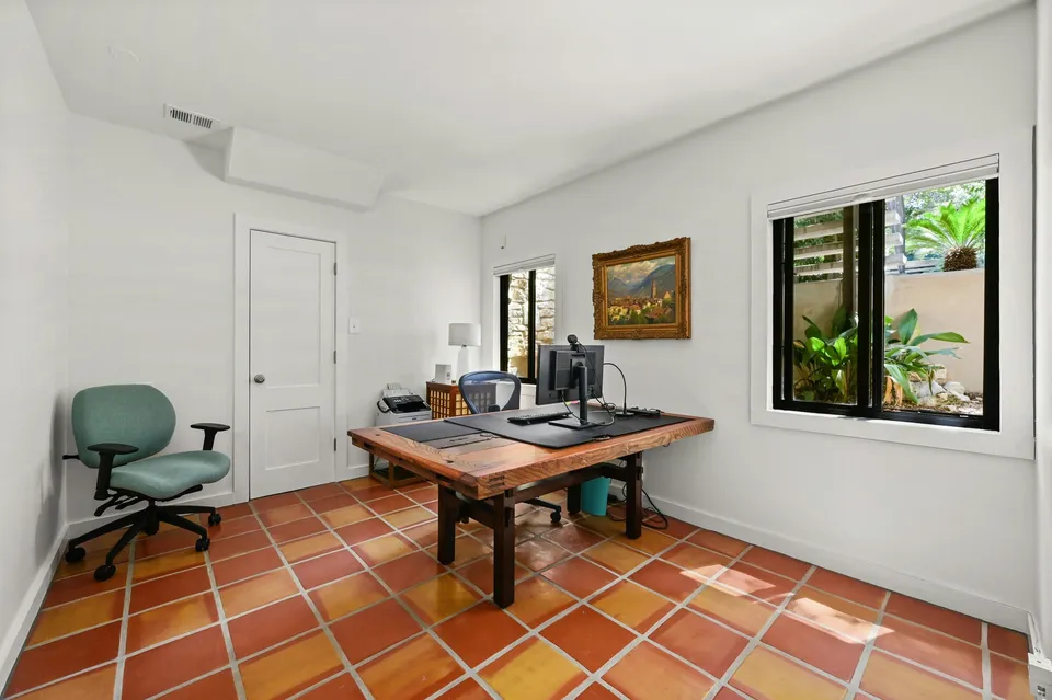 Craft room with Saltillo tile floors, a wood desk and a window
