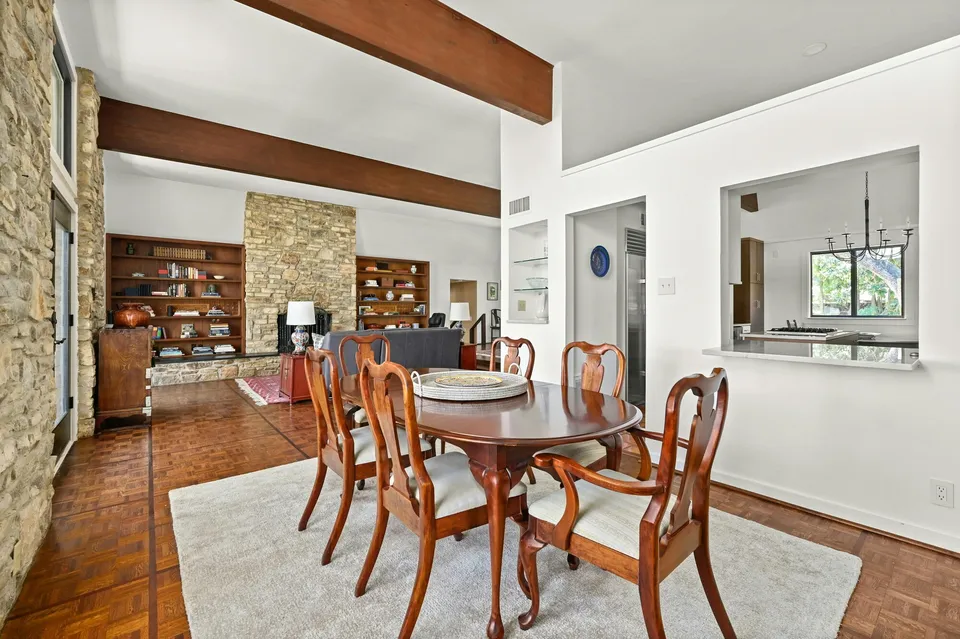 Dining room with a round table past exposed beams and a stone wall