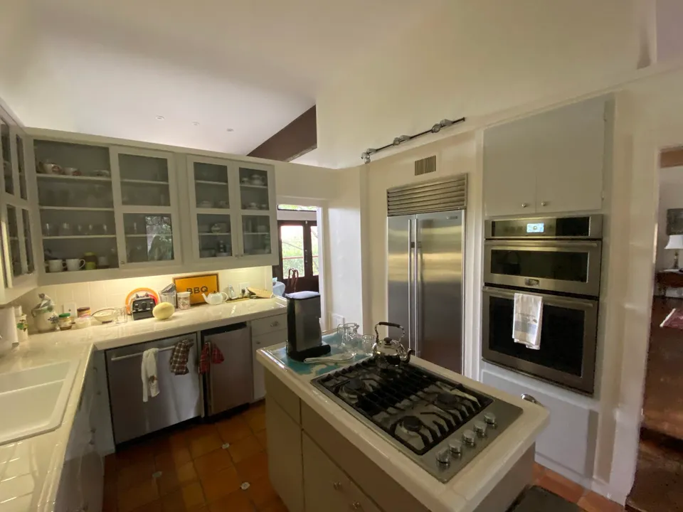 Kitchen before the remodel, with pale green cabinets, a cooktop peninsula and Saltillo tile