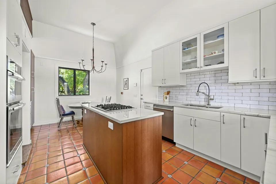Kitchen with white cabinets, a wood island and a chandelier over a table