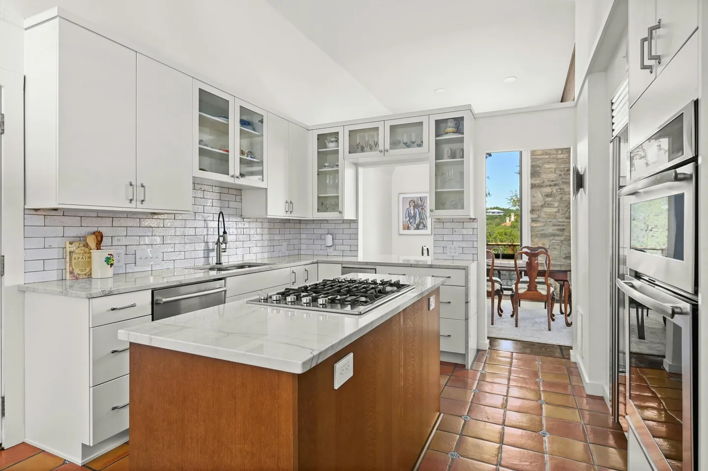 Kitchen with white cabinets, a wood island with a cooktop and a white subway tile backsplash