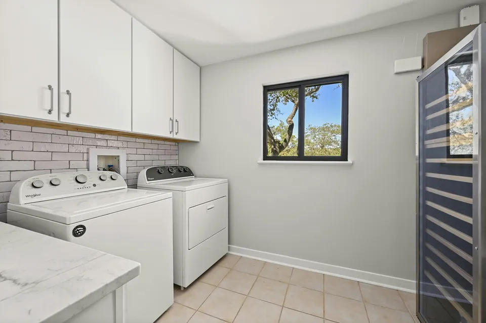 Laundry room with white cabinets, a brick backsplash and a wine fridge