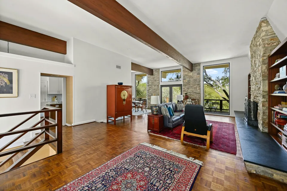 Living room with parquet floors, a stone fireplace and a red rug